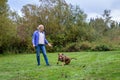 Mature woman playing fetch with her Doberman mix dog in a grassy green space in the park Royalty Free Stock Photo
