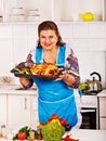 Mature woman preparing chicken at kitchen.