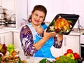 Mature woman preparing chicken at kitchen.