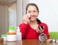 Mature woman puts facepowder on face