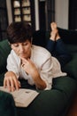 Mature woman reading book while lying on couch Royalty Free Stock Photo