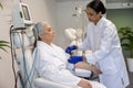 Mature woman receiving intravenous vitamin therapy in hospital room sitting in armchair. Royalty Free Stock Photo