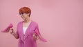 Mature woman with red short hair holding high heal shoes Isolated on purple background