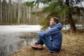 Mature woman relaxing on shore of forest lake on early springtime. Outdoor activity