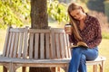Mature Woman Relaxing Sitting On Park Bench Under Tree Reading Book With Takeaway Coffee Royalty Free Stock Photo