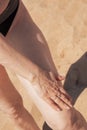 Mature woman with sagging skin smears her legs with sunscreen. Protecting the skin from the bright sun Royalty Free Stock Photo