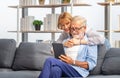 Mature woman and senior man using smartphone talking on video call on cozy sofa at home, Portrait of Cheerful senior couple in Royalty Free Stock Photo