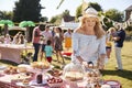 Mature Woman Serving On Cake Stall At Busy Summer Garden Fete