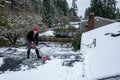 Mature woman shoveling fresh wet snow off a flat carport roof