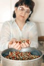 A mature woman sits at a table on which stands a container with ripe wild strawberries Royalty Free Stock Photo