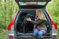 Mature Woman Sitting With Black Labrador In Back Of Car Before Going On Walk In Countryside