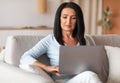 Mature woman sitting on couch and working on computer Royalty Free Stock Photo