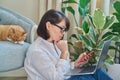 Mature woman sitting at home, using smartphone laptop Royalty Free Stock Photo