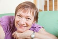 Mature woman sitting on sofa and smiling Royalty Free Stock Photo