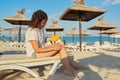 Mature woman sitting onsun lounger on sandy beach applying sunscreen to her leg Royalty Free Stock Photo