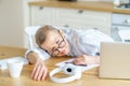 Mature woman sleeping on table in kitchen at home, taking a break while working or studying online Royalty Free Stock Photo