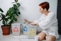 Mature woman sorting garbage beween small recycle bins at home Royalty Free Stock Photo