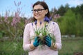 Mature woman in spring garden with gloves plant blue flowers mouse hyacinth