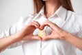 Cryptocurrency. Woman standing isolated on white holding electronic cash in heart shape close-up
