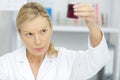 mature woman standing at microscope and examining flask Royalty Free Stock Photo