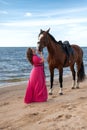 Mature woman stands on the beach with a brown horse Royalty Free Stock Photo