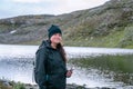 Mature woman stands and looking forward, hiking high in Norwegian mountains. High altitude terrain, mountain glacier lake. Royalty Free Stock Photo