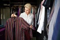 Mature Woman stylist organizes or chooses clothes outfit and tries on in large wardrobe closet at home Royalty Free Stock Photo