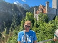 Mature woman in sunglasses over a picturesque cliff, smiling. On the mountain near Neuschwanstein Royalty Free Stock Photo