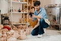 Mature woman taking picture of handcrafts at pottery workshop