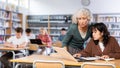 Mature woman teacher cheks the assignment from a schoolgirl Royalty Free Stock Photo