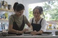 Mature woman teaching young woman making ceramics in pottery workshop