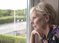 Mature woman thinking and looking out of a window Royalty Free Stock Photo