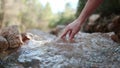 Mature woman touching and scooping up the purest transparent water in a mountain river flowing among the stones