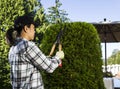 Mature woman Trimming the Hedges near her patio