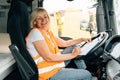 Mature woman truck driver steering wheel inside lorry cabin. Happy middle age female trucker portrait Royalty Free Stock Photo