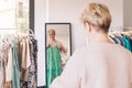 mature woman trying on clothes in front of a mirror. blonde woman shopping in a fashion shop. shopping concept.