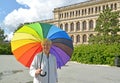A mature woman under a rainbow umbrella stands against the background of the exchange building. Kaliningrad Royalty Free Stock Photo