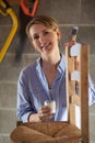 Portrait Of Mature Woman Upcycling Furniture In Workshop At Home Painting Wooden Chair