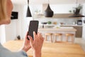 Mature Woman Using App On Mobile Phone To Control Central Heating Temperature In House Royalty Free Stock Photo