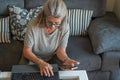 mature woman using cell phone and laptop while sitted on the coach Royalty Free Stock Photo