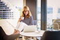 Mature woman using her laptop while sitting in the armchair by the window at home Royalty Free Stock Photo