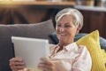 Woman using tablet computer while relaxing on sofa at home Royalty Free Stock Photo