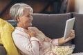 Woman using tablet computer while relaxing on sofa at home Royalty Free Stock Photo