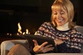 Mature woman using tablet in front of fire at home