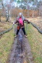 Mature woman walking with difficulty a narrow ground muddy pedestrian path