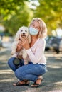 Mature woman walking with a dog outdoors an antivirus mask Royalty Free Stock Photo