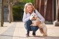 Mature woman walking with fluffy white dog in summer city