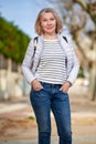 Mature woman walking with fluffy white dog in summer city