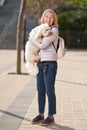 Mature woman walking with fluffy white dog in summer city