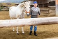 Mature woman walking white horse in paddock Royalty Free Stock Photo